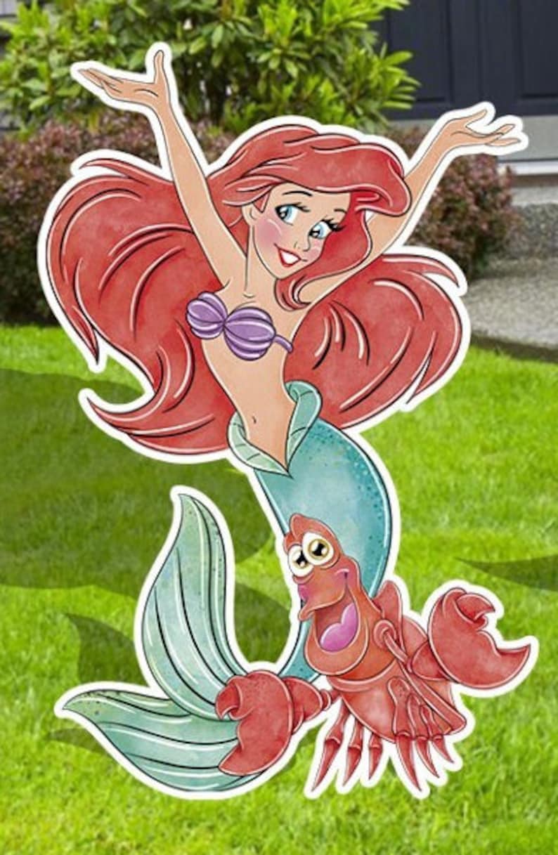 Puede incluir: Ariel, la Sirenita, con cabello rojo y un sujetador de concha p&uacute;rpura, se muestra con su amigo el cangrejo Sebasti&aacute;n. Ariel sonr&iacute;e y tiene los brazos levantados. Sebasti&aacute;n es rojo y tiene ojos grandes y redondos.