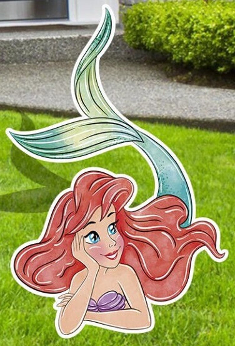 Puede incluir: Una ilustraci&oacute;n de dibujos animados de Ariel, la Sirenita, con el pelo largo y rojo y una cola verde. Lleva un sujetador de concha p&uacute;rpura y mira hacia arriba con una expresi&oacute;n so&ntilde;adora.