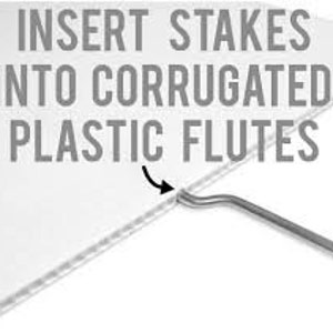 May include: A white corrugated plastic sheet with a metal stake being inserted into the flutes. The text INSERT STAKES INTO CORRUGATED PLASTIC FLUTES is printed in gray capital letters above the stake, with a black arrow pointing to the insertion point.