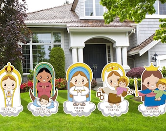 May include: Five colorful cardboard cutouts of religious figures, each with a different name and title. The figures are standing on a green lawn in front of a house. The figures are all wearing crowns and robes. The names of the figures are "Virgen de Fatima", "Virgen de Guadalupe", "Virgen Maria", "Virgen del Carmen", and "Maria Auxiliadora".