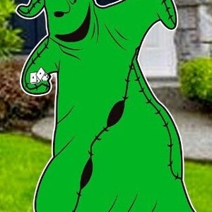K&ouml;nnte beinhalten: Eine gr&uuml;ne, gen&auml;hte Comicfigur mit einem breiten L&auml;cheln und einem schwarzen Augenklappen. Die Figur h&auml;lt einen Stapel wei&szlig;er Karten in ihrer rechten Hand. Die Figur steht auf einem gr&uuml;nen Rasen.