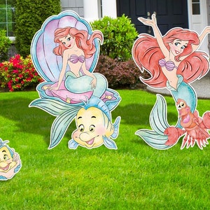 Puede incluir: Conjunto de cuatro recortes de madera con Ariel, la Sirenita, en varias poses. Los recortes est&aacute;n pintados en estilo acuarela con tonos de rosa, azul y verde. Ariel se muestra sentada en una concha, nadando y sosteniendo un cangrejo y un pez.