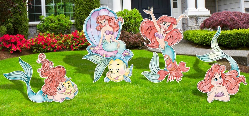 Puede incluir: Conjunto de cuatro recortes de madera con Ariel, la Sirenita, en varias poses. Los recortes est&aacute;n pintados en estilo acuarela con tonos de rosa, azul y verde. Ariel se muestra sentada en una concha, nadando y sosteniendo un cangrejo y un pez.