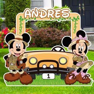 May include: A photo booth prop featuring Mickey Mouse and Minnie Mouse dressed in safari outfits. The prop includes a yellow jeep with a frame for a photo. The text "ANDRES" is at the top of the frame.