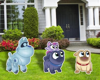 May include: Three cartoon dog yard decorations. One is a light blue robot dog, another is a dark blue dog with a purple cat on its back, and the third is a tan dog with a red collar. They are on a green lawn.