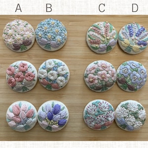 Puede incluir: Doce botones de tela bordados con diferentes dise&ntilde;os florales. Los botones est&aacute;n dispuestos en cuatro filas de tres botones cada una. Los botones son todos redondos y tienen un fondo blanco. Los dise&ntilde;os florales son todos diferentes e incluyen rosas, margaritas, tulipanes y otras flores. Los botones est&aacute;n todos hechos a mano y son perfectos para agregar un toque de elegancia a cualquier proyecto.