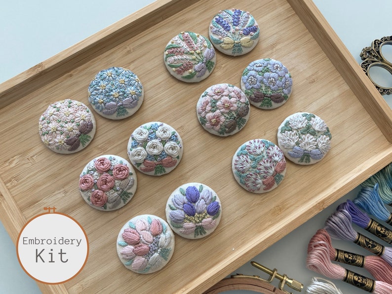 Puede incluir: Un conjunto de 10 kits de bordado con diferentes dise&ntilde;os florales. Cada kit incluye una pieza de tela precortada con un dise&ntilde;o floral, hilo de bordar y una aguja. Los kits est&aacute;n dispuestos en una bandeja de madera.