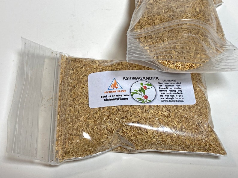 Puede incluir: Una bolsa de pl&aacute;stico transparente llena de hierba de Ashwagandha seca de color marr&oacute;n claro. La bolsa tiene una etiqueta con el texto "Ashwagandha" y "AlchemyFlame" con una peque&ntilde;a imagen de una planta de bayas rojas.