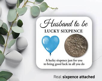 May include: A card with a blue heart balloon and a silver sixpence coin. The card says "Husband to be Lucky Sixpence" and "A lucky sixpence just for you to bring good luck in all you do." The card also says "Real sixpence attached."