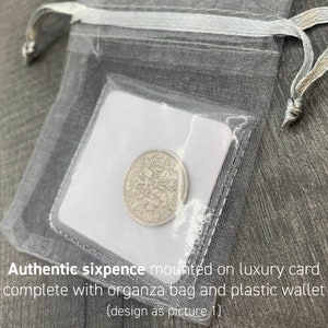 May include: A silver sixpence coin is displayed inside a clear plastic wallet, set on a white card. The wallet is inside a sheer, gray organza bag with a drawstring closure. Text on the card reads: "Authentic sixpence mounted on luxury card complete with organza bag and plastic wallet (design as picture 1)".