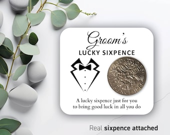 May include: A white card with black text that reads "Groom's Lucky Sixpence". A black and white illustration of a tuxedo bow tie is on the card. A silver sixpence coin is attached to the card. The text "A lucky sixpence just for you to bring good luck in all you do" is on the card. The text "Real sixpence attached" is on the card.