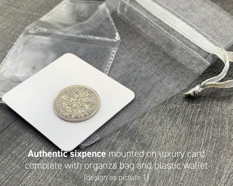 May include: An authentic sixpence coin mounted on a white luxury card, presented with an organza bag and a plastic wallet. The coin is silver-colored and features intricate details. The text "Authentic sixpence mounted on luxury card" is visible.