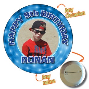 Pode incluir: Botão redondo azul e branco com uma foto de um menino usando óculos de sol e um chapéu. O botão diz "Happy 9th Birthday RONAN" em texto azul.