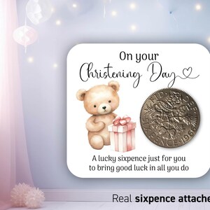 Può includere: Un biglietto con un orsacchiotto che tiene una scatola regalo rosa e una moneta di sei pence vintage. Il biglietto dice "On your Christening Day" e "A lucky sixpence just for you to bring good luck in all you do." Il biglietto dice anche "Real sixpence attached."