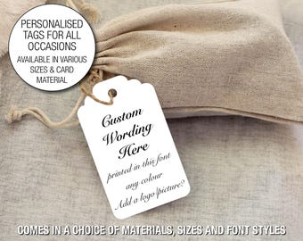May include: A white tag with scalloped edges, featuring the text "Custom Wording Here" in elegant script, with additional text about font, color, and logo options. The tag is attached to a drawstring bag. Text on the image reads: "PERSONALISED TAGS FOR ALL OCCASIONS".