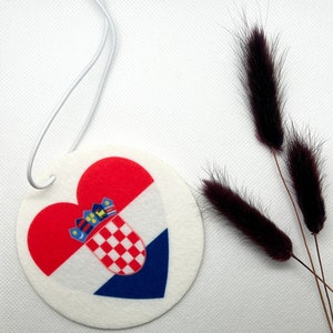 Könnte beinhalten: Ein runder weißer Auto-Lufterfrischer mit einem rot-weiß-blauen kroatischen Flaggen-Design in Herzform. Der Lufterfrischer hängt an einer weißen Schnur.