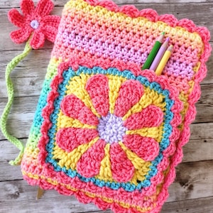 May include: A crocheted rainbow colored book cover with a flower design and a pocket for pencils. The cover has a matching flower bookmark.