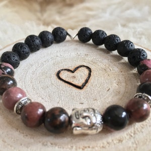 Könnte beinhalten: Ein Armband mit schwarzen Lavasteinen, rosafarbenen und braunen Edelsteinperlen und einem silbernen Buddha-Anhänger.