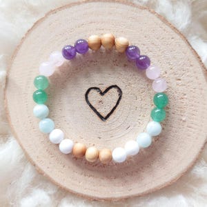 Könnte beinhalten: Ein Armband aus Amethyst, Rosenquarz, Aventurin, Aquamarin, weißem Howlith und Holzperlen.