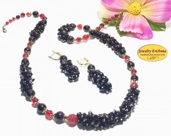 Könnte beinhalten: Ein Granat-Schmuckset mit einer Halskette, Ohrringen und einem Armband. Die Halskette und die Ohrringe sind aus kleinen, dunkelroten Granatperlen gefertigt, während das Armband aus größeren, roten Granatperlen besteht. Das Set ist mit goldfarbenem Metall verziert.