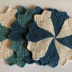 K&ouml;nnte beinhalten: Set aus vier geh&auml;kelten Platzsets in einem Teal- und Cremefarbton. Die Platzsets sind sternf&ouml;rmig und haben ein Spiraldesign.