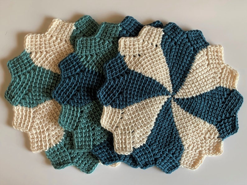 K&ouml;nnte beinhalten: Set aus vier geh&auml;kelten Platzsets in einem Teal- und Cremefarbton. Die Platzsets sind sternf&ouml;rmig und haben ein Spiraldesign.