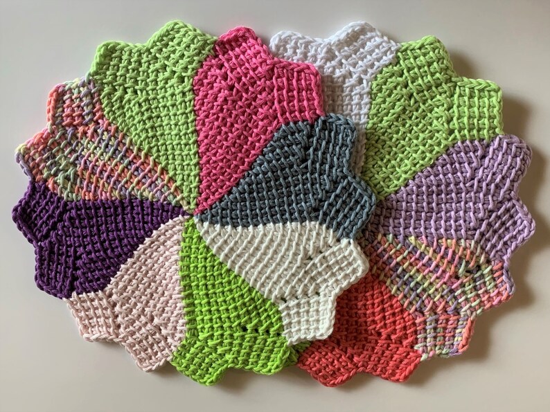 K&ouml;nnte beinhalten: Ein Set aus sechs geh&auml;kelten Untersetzern in verschiedenen Farben, darunter Rosa, Gr&uuml;n, Lila, Wei&szlig; und Grau. Die Untersetzer sind sternf&ouml;rmig und haben einen gewellten Rand.