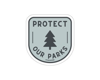 May include: A gray and white sticker with the text "Protect Our Parks" and a stylized pine tree. The text "Of Wild Nature" is at the bottom of the sticker.