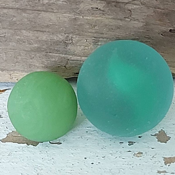 Mini opaque green seaglass marble and green cats eye marble both perfectly frosted weathered and worn by the waves and turf of the ocean