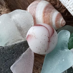 Odd opaque white and brown Seaglass marble. This must have been a dudd due to one flat side. Such a unique piece of history