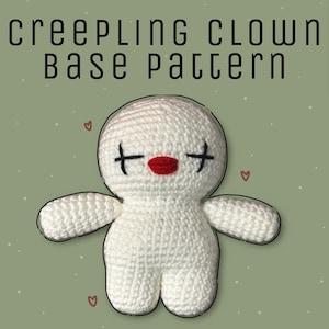 Op de afbeelding: Witte gehaakte pop met rode lippen en zwarte ogen. De pop heeft een eenvoudig ontwerp en is een basispatroon voor een griezelige clown.