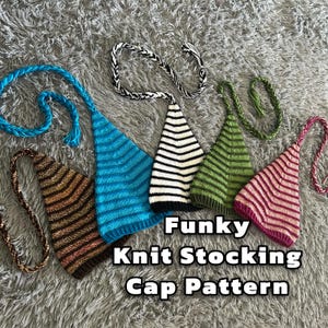 Puede incluir: Cinco gorros de punto de estilo calcetín en diferentes colores y patrones, incluyendo azul, blanco, verde, rosa y marrón. Los gorros tienen lazos largos y están dispuestos sobre una superficie gris y peluda. El texto "Funky Knit Stocking Cap Pattern" está escrito debajo de los gorros.