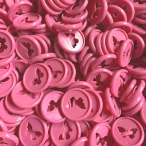 K&ouml;nnte beinhalten: Ein gro&szlig;er Haufen rosa Plastikkn&ouml;pfe mit einem Schmetterlingsdesign.