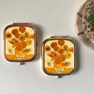 Peut inclure: Deux miroirs compacts dor&eacute;s avec un motif de tournesol. Les miroirs ont un motif floral avec le nom "Hailey" imprim&eacute; en bas.