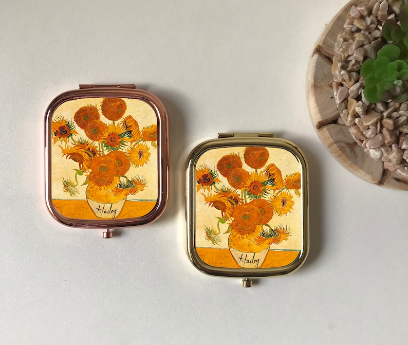 Peut inclure: Deux miroirs compacts dor&eacute;s avec un motif de tournesol. Les miroirs ont un motif floral avec le nom "Hailey" imprim&eacute; en bas.