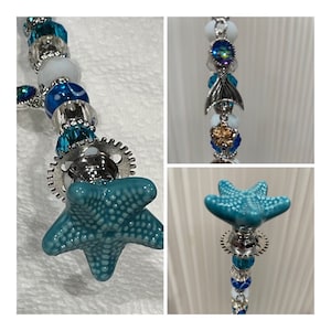 May include: A teal blue starfish charm with a silver gear and beads in shades of blue and white.