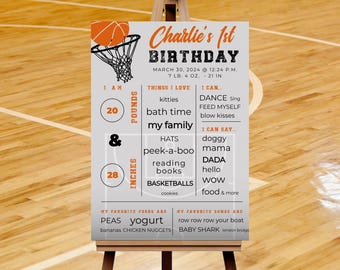 May include: A gray and orange printable birthday sign for a baby boy's first birthday. The sign features a basketball hoop and ball, and includes the baby's name, age, date of birth, weight, height, favorite foods, and songs. The text reads "Charlie's 1st Birthday, March 30, 2024, 12:24 PM, 7 lb. 4 oz., 21 in., I am 20 pounds & 28 inches, Things I love: kitties, bath time, my family, Hats, peek-a-boo, reading books, basketballs, cookies, I can: dance, feed myself, blow kisses, I can say: doggy, mama, dada, hello, wow, food & more, My favorite foods are: peas, yogurt, bananas, chicken nuggets, My favorite songs are: row row row your boat, baby shark, london bridge."