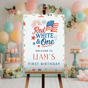 Puede incluir: Un letrero de fiesta en un caballete con el texto "Red, White & One" y "Liam's First Birthday" en rojo y azul. El letrero presenta una bandera estadounidense y gr&aacute;ficos de estrellas, rodeado de globos en colores pastel.