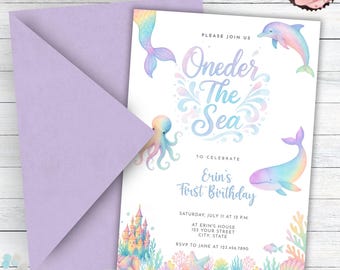 May include: A lilac envelope beside a birthday invitation with the text "Oneder The Sea" and "Erin's First Birthday". The invitation features watercolour illustrations of a mermaid's tail, dolphin, octopus, and whale. A cupcake with pink icing is in the top right corner.