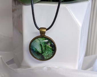 Abstract alcohol ink round pendant in shades of green and gold. Original wearable art pendant. Antique bronze setting.