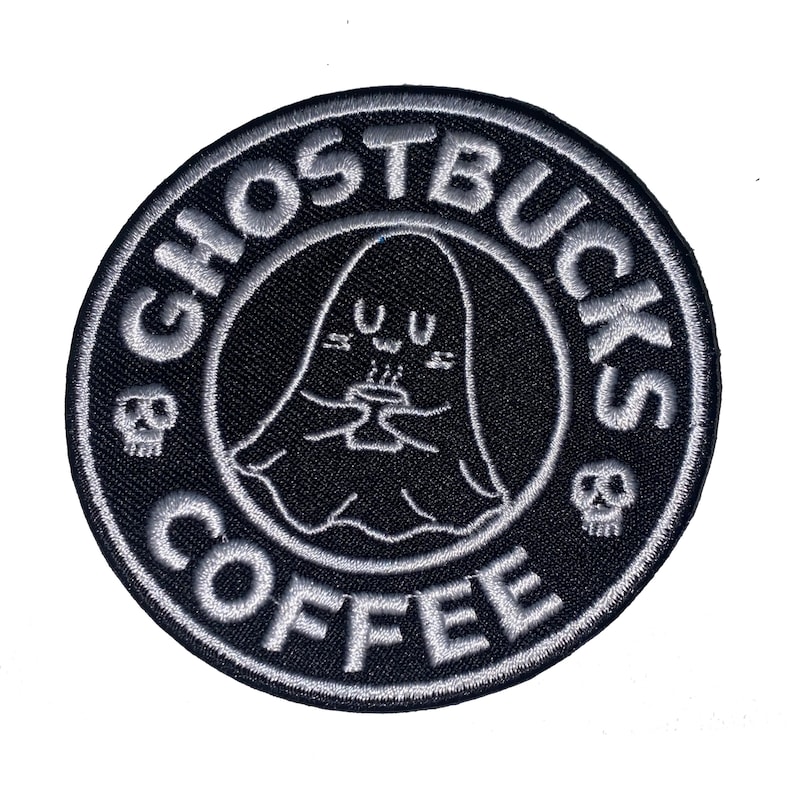 Peut inclure: &Eacute;cusson brod&eacute; noir et blanc avec le texte "GHOSTBUCKS COFFEE" dans un cercle. Il pr&eacute;sente un fant&ocirc;me de dessin anim&eacute; tenant une tasse, avec des ic&ocirc;nes de cr&acirc;ne de chaque c&ocirc;t&eacute;.