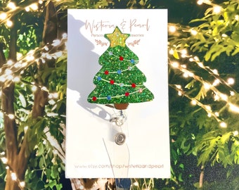 Könnte beinhalten: Ein grüner Glitzer-Weihnachtsbaum mit roten und blauen Kugeln und einem goldenen Stern oben. Der Baum ist an einem einziehbaren Ausweishalter mit einem silbernen Clip befestigt. Die Karte lautet "Wisteria & Pearl Personal Accessories" und "www.etsy.com/shop/wisteriaandpearl".