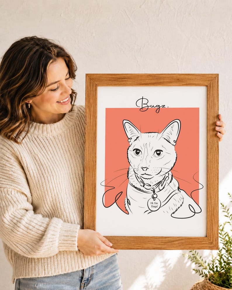 Puede incluir: Una l&aacute;mina de arte enmarcada con una ilustraci&oacute;n de l&iacute;nea negra de un gato sobre un fondo cuadrado color coral. El nombre Bugz est&aacute; escrito en cursiva sobre el gato, que lleva una placa en el collar con el texto Hi, I'm Bugz.