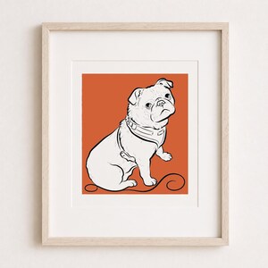 Puede incluir: Una l&aacute;mina de arte enmarcada que presenta un dibujo de l&iacute;neas en blanco y negro de un pug con arn&eacute;s, sobre un fondo de color naranja quemado s&oacute;lido. El pug se muestra en posici&oacute;n sentada con una correa que se extiende por el borde inferior.