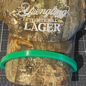 May include: A camouflage baseball cap with a white embroidered logo that reads "Yuengling Traditional Lager".