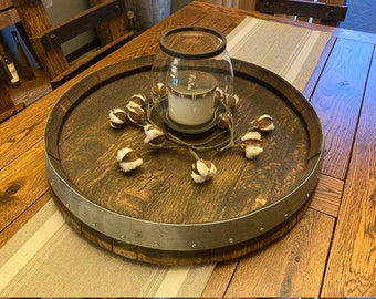 May include: A wooden barrel tray with a silver metal band and decorative studs. The tray is decorated with cotton bolls and a glass candle holder with a white candle.