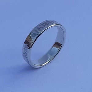 Può includere: Un anello d'argento con una texture martellata. L'anello è semplice ed elegante.