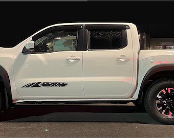 May include: White pickup truck with black accents and "PRO 4X" lettering on the side. The truck has black wheels with a machined face and black side steps.