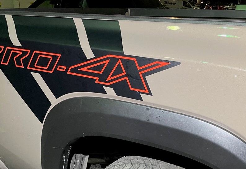 Puede incluir: Primer plano de una caja de cami&oacute;n con un dise&ntilde;o gr&aacute;fico en blanco y negro y el texto "PRO.4X" en rojo.