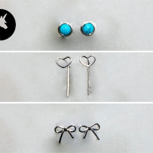 May include: Three pairs of silver earrings. The first pair features turquoise stones. The second pair has heart-shaped designs. The third pair has bow-shaped designs.